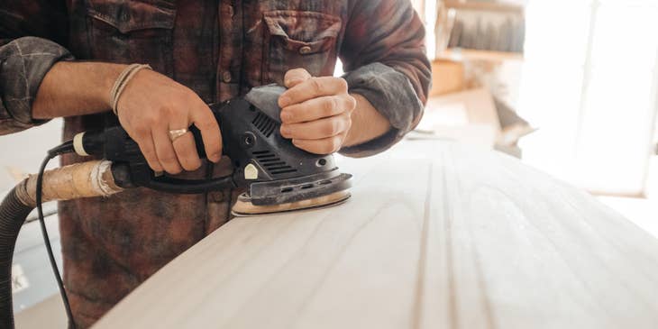 Journeyman carpenter sanding down a wooden board