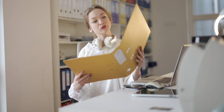 Junior accountant checks submitted receipts and file invoices in a binder to submit a financial report to the manager