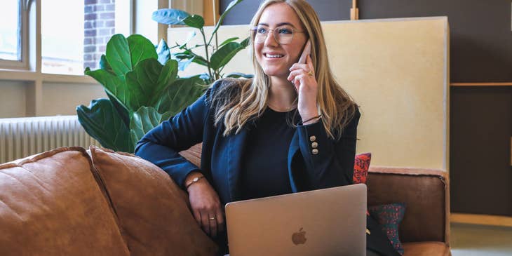 A Junior Recruiter on her laptop while talking on her mobile phone.