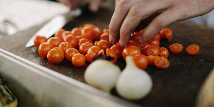 A kitchen helper chopping tomatoes.