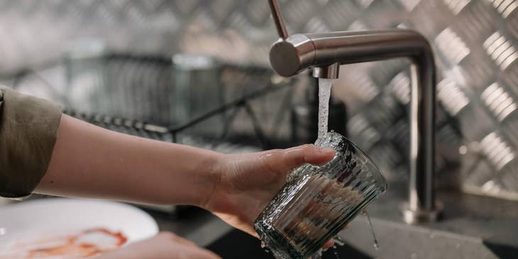 A kitchen porter washing a glass.