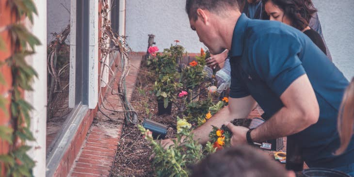 Landscape foreman tending to a plant box with other landscapers