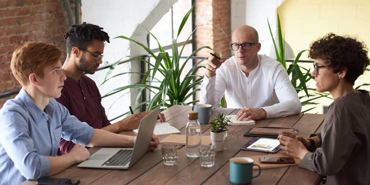 a group of writers in a meeting with their Managing Editor to keep up with updates and new projects on their company