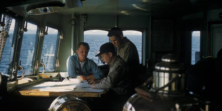 Marine Engineer discussing with his assistants the floor plan of the ship for maintenance checkup