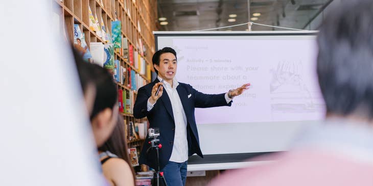 male mentor giving a lecture beside a projector screen