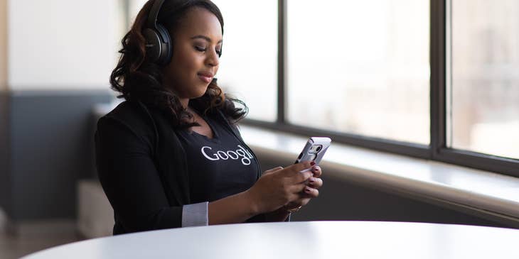 Mobile test engineer wearing a headset while holding and looking at her mobile phone as she conducts system tests.