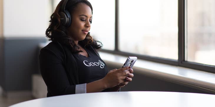 Mobile test engineer wearing a headset while holding and looking at her mobile phone as she conducts system tests