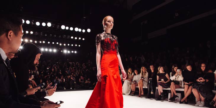 a model wearing a red gown walking on a catwalk for a year-end fashion show