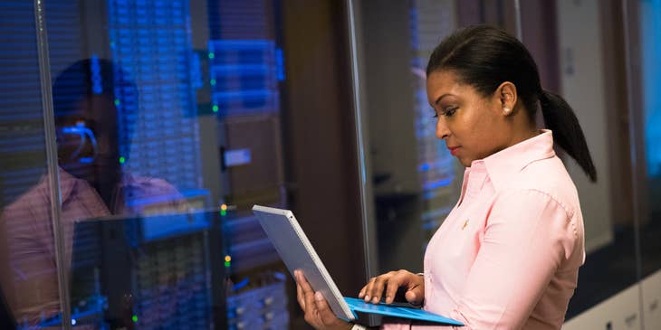 female network administrator performing a maintenance check on the company's server using her laptop
