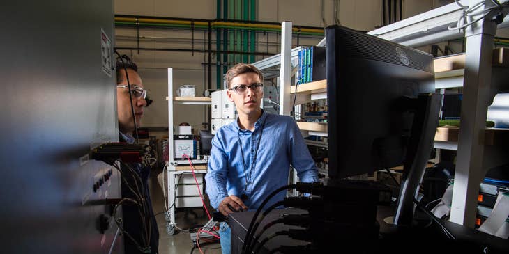 Two nuclear engineers checking the results of a newly developed system while standing and looking in front of a computer