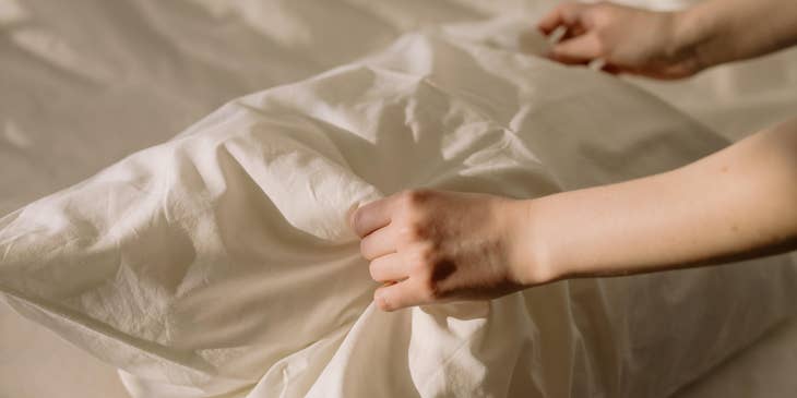 Nurse technician changes the bedsheet for the patient.