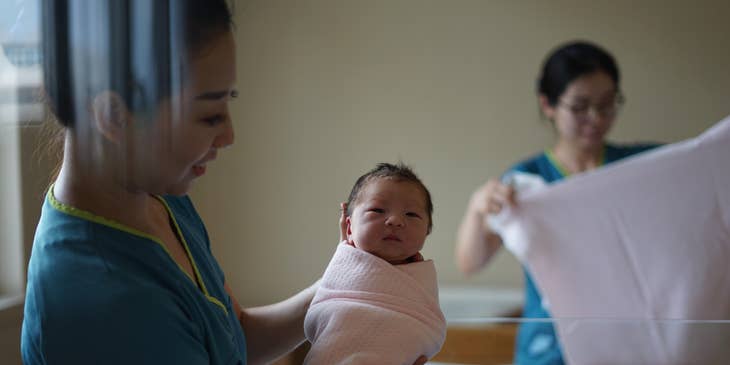 Nursery nurse showing the baby to the visitors.