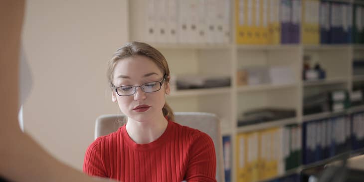 Payroll administrator checks timesheets while answering questions about payroll concerns