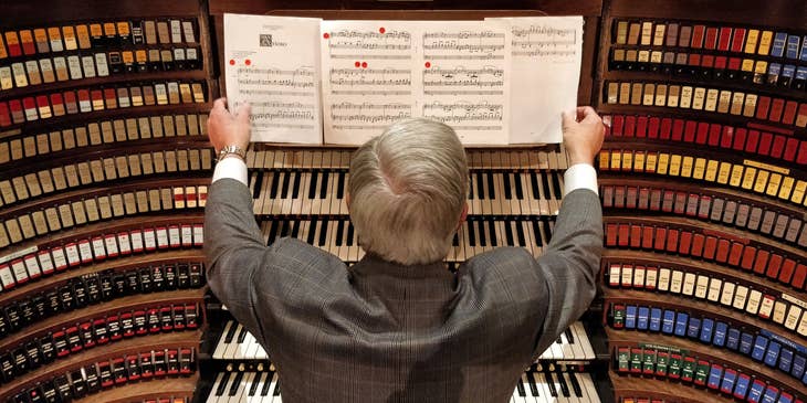 Pianist holding sheet music in front of a piano