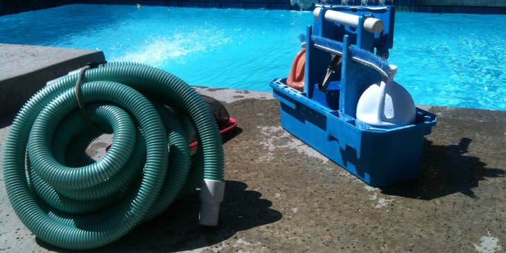 cleaning equipment of a pool service technician beside a swimming pool