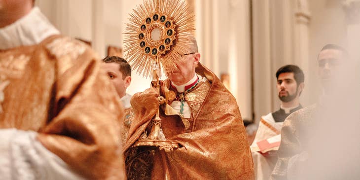 A priest holding the golden cross during the opening of the mass.