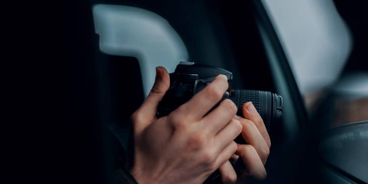 A private investigator working undercover doing surveillance and taking photos inside a vehicle.