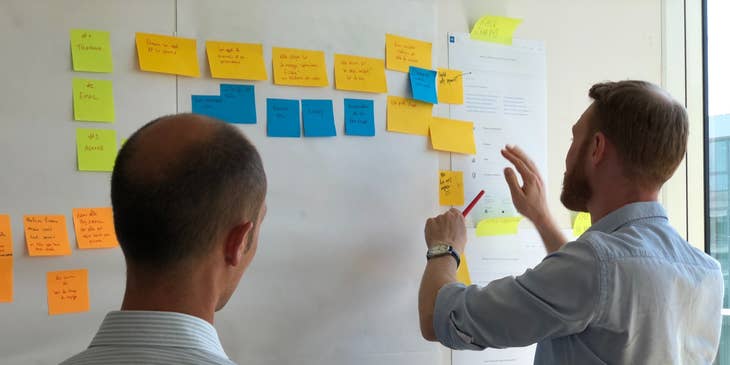 Product owner checking the development process of his project while his colleague is looking on