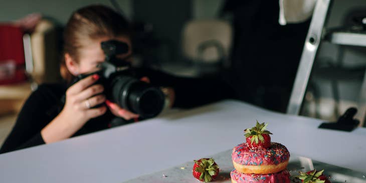 A product photographer taking photos of strawberry donuts for the newly opened doughnut shop.