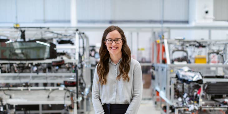 female production engineer standing in workshop with the manufactured products behind her