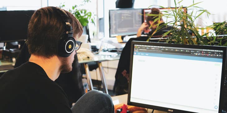 QA automation engineer wearing a headset and working on test designs at his workstation