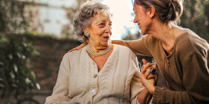 Residential Aide smiling at a female woman while holding her hand