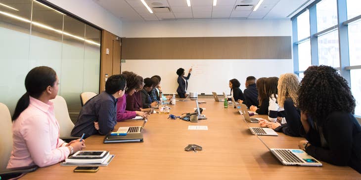 A female retirement specialist conducting a conference meeting with a group of employees.