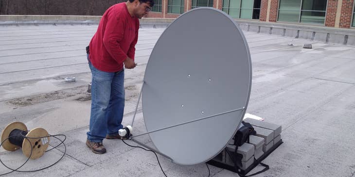 Satellite technician repairing a satellite dish
