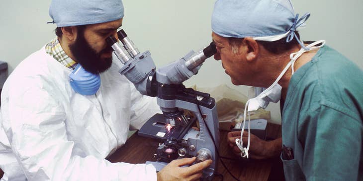 Physiologist is studying a bacteria under the microscope with an assistant.