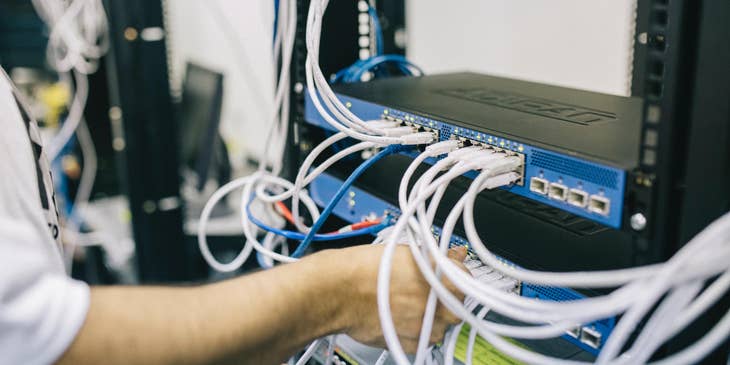 Senior network engineer connecting the cables to the router as to configure the network connection