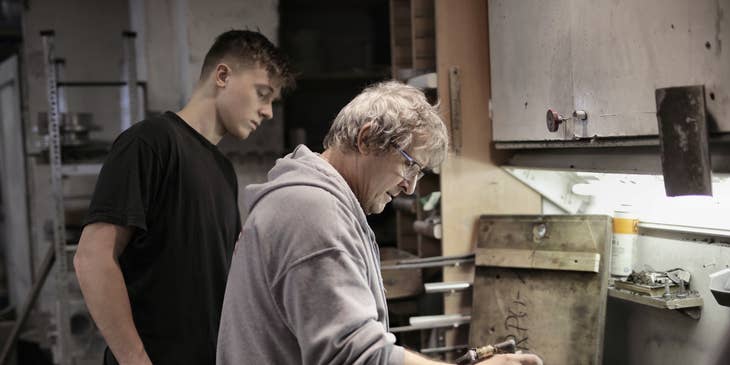 Shop foreman showing an apprentice how to operate the shop's machinery