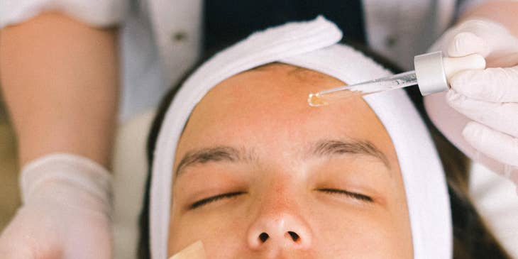 Skincare specialist applying skin products to a patient's skin.