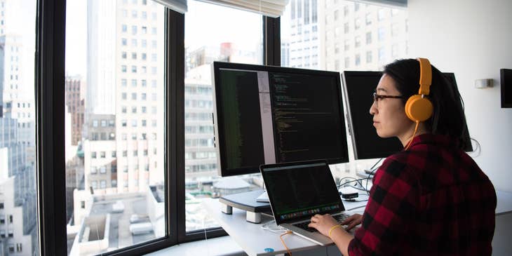 software project manager working behind computer screens in a building with a city view