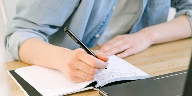 A Staffing Coordinator writing on a notebook.