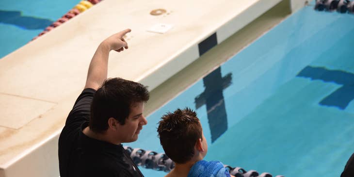 Swimming coach giving instructions to a young student