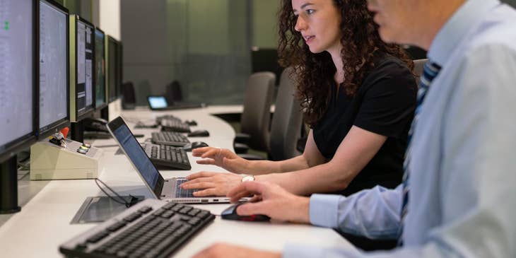 Systems analyst working with a colleague evaluating current IT systems while preparing for a software upgrade