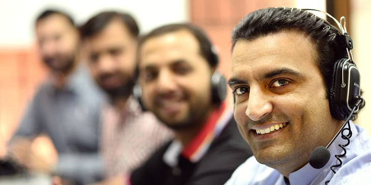 a team of Telemarketers wearing headphones and smiling