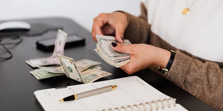 female teller counting dollar bills on the table