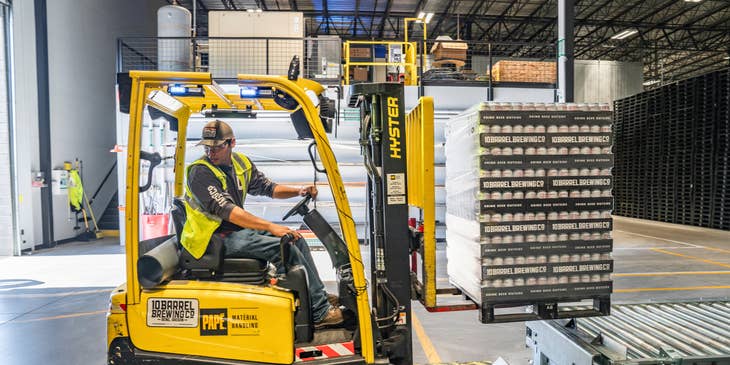 Warehouse worker stacking products using forklift