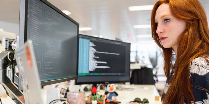 a Web Developer coding using her dual screen monitor and a MacBook