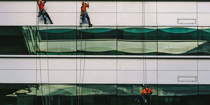 Window cleaning technicians working on a high building